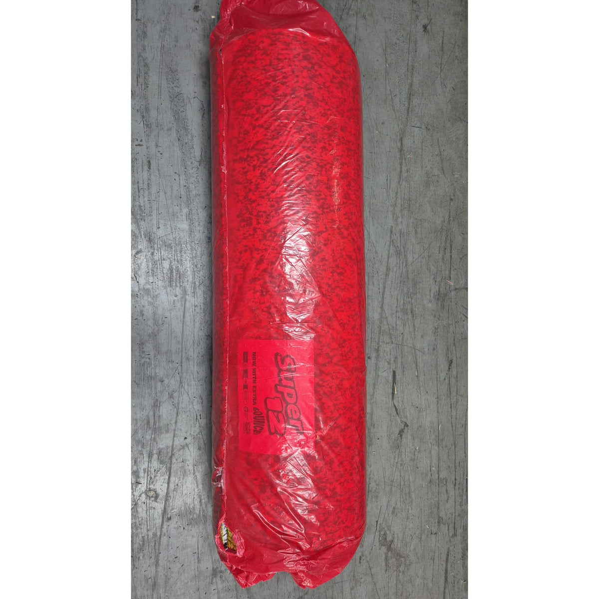 Red object wrapped in plastic on a gray concrete surface